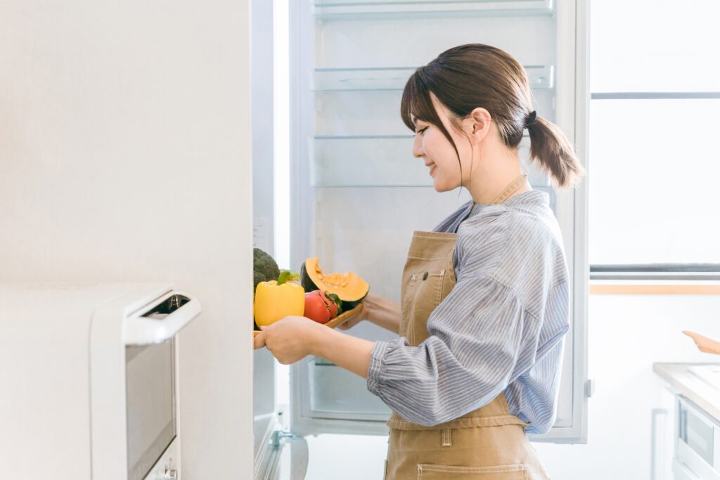 冷蔵庫に野菜を入れる女性