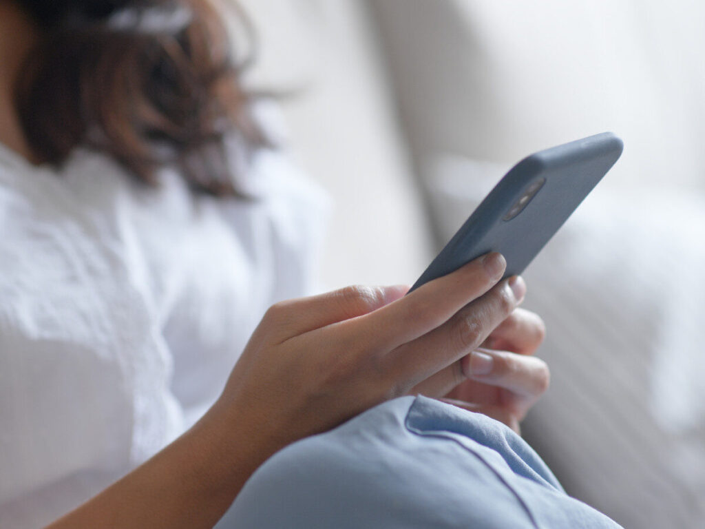 ソファでスマホを操作する女性の手元アップ