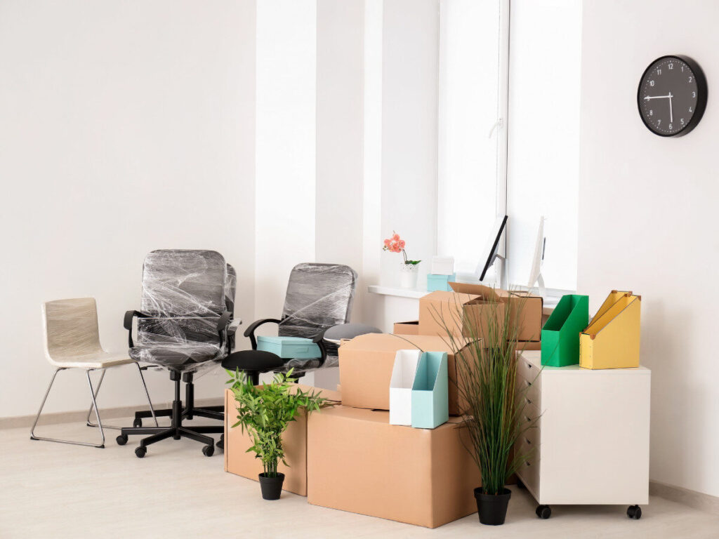 引っ越し準備中のオフィス家具と段ボールが並んだ室内