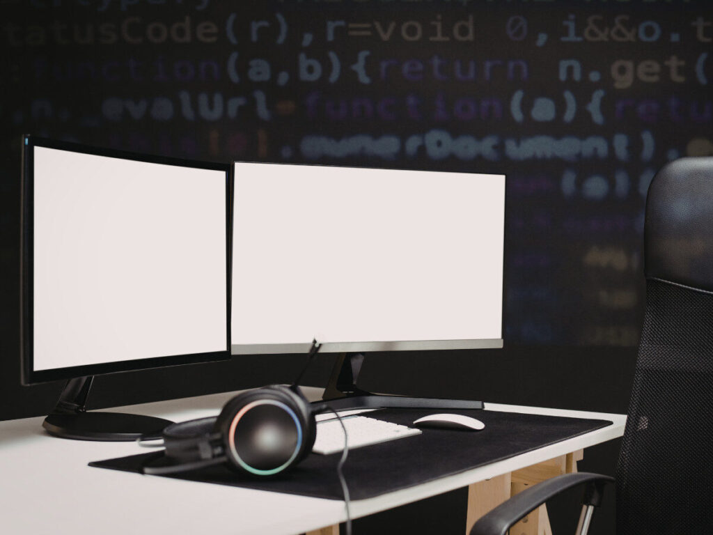 ヘッドホンが置かれたデュアルモニターのPCデスク環境