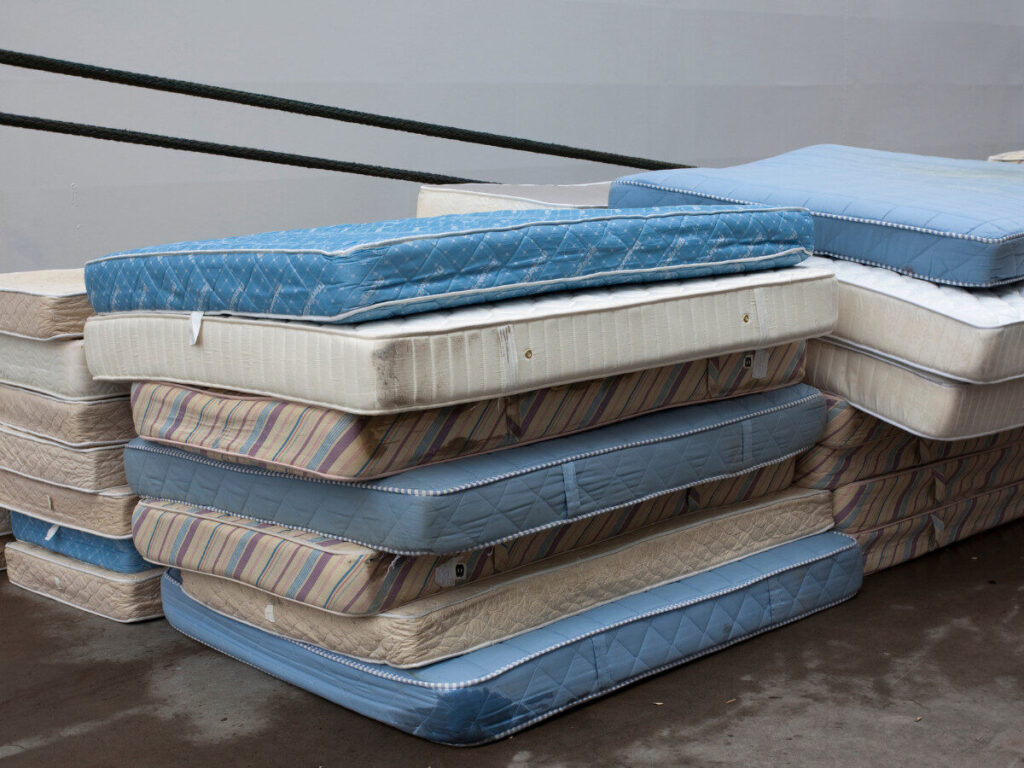 屋外に積み上げられた複数の不要マットレス