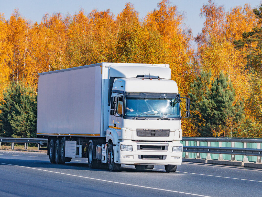 秋の木々を背景に走る大型引っ越しトラック