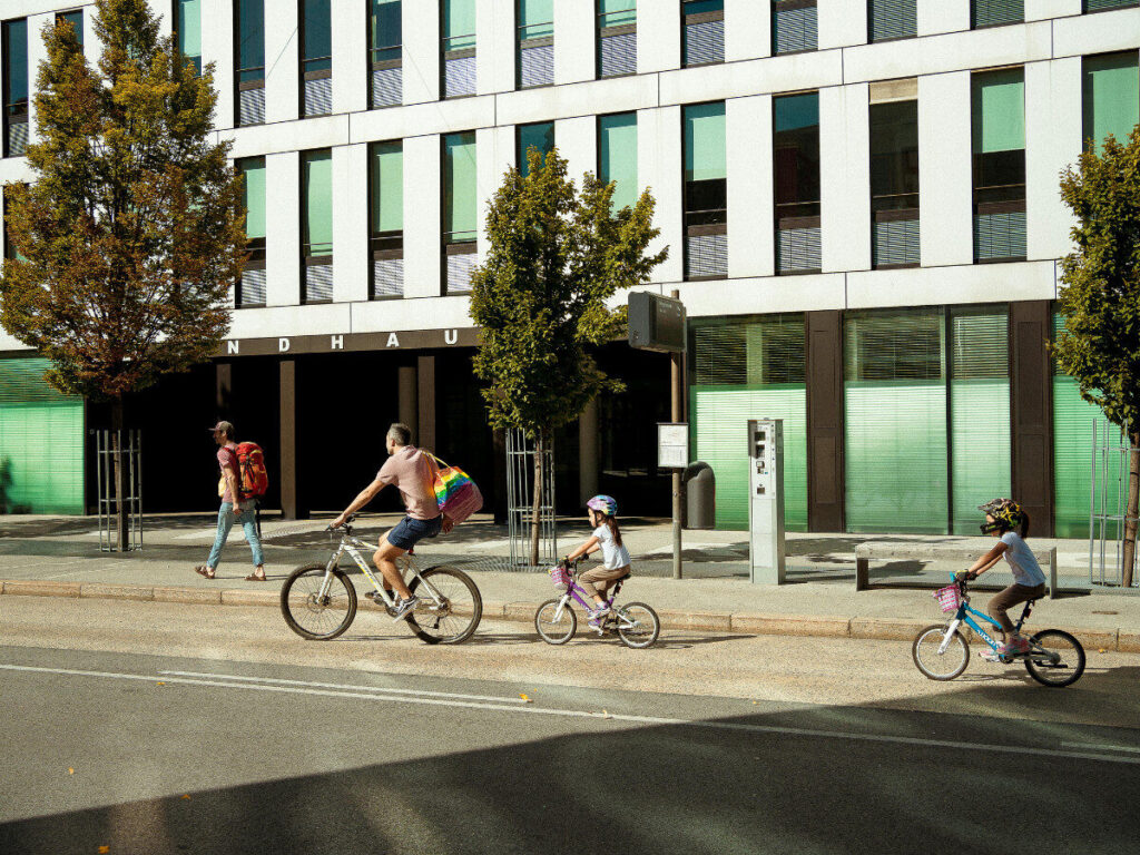 都市の道路を親子で走る自転車の光景