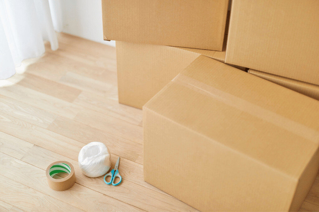 引っ越し準備のために段ボール箱とガムテープ、ひも、ハサミを並べた写真