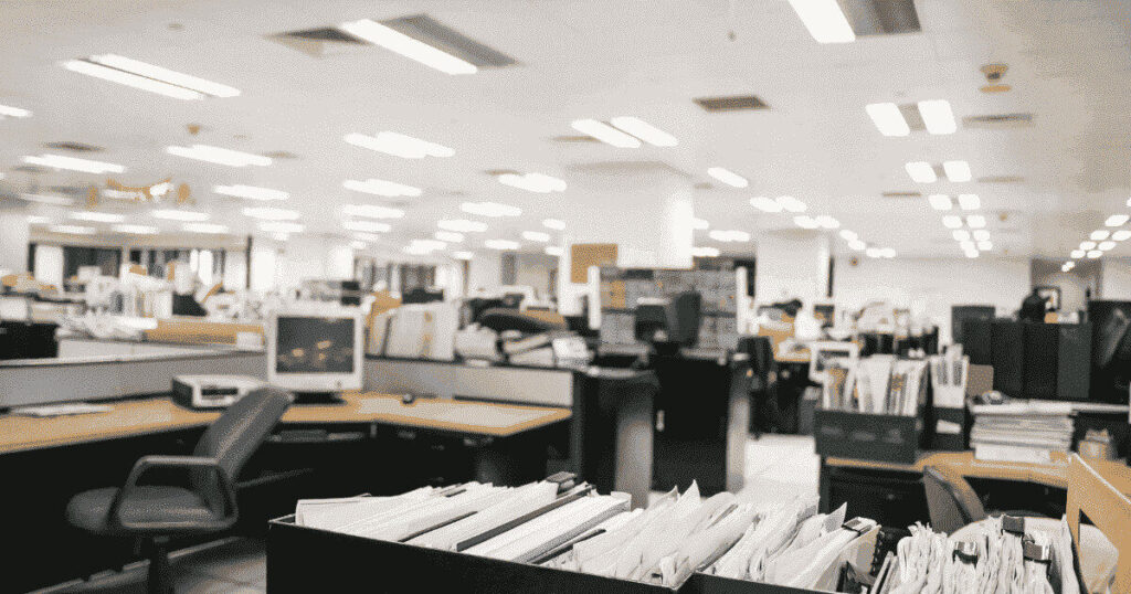 仕切りと書類で埋め尽くされた広いオフィスフロア