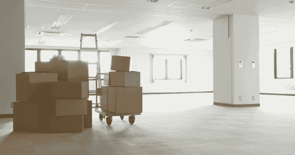 移転準備中の空きオフィスと台車に積まれた段ボール