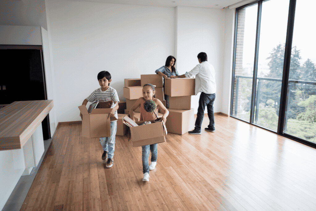 新居で家族が段ボールを運びながら引っ越し作業をしている写真