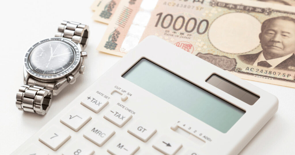 腕時計と日本円の紙幣、査定金額を計算する電卓