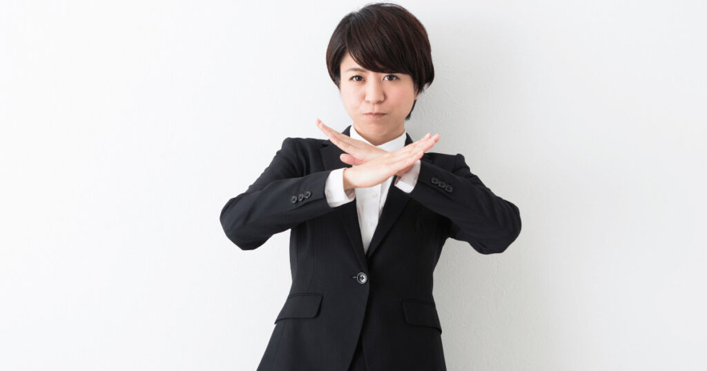 腕でバツ印を作り、買取できないことを示す女性